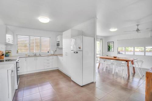 a white kitchen with a table and a refrigerator at 13 Indigo Avenue - 'Indigo Sands' - Rainbow Beach in Rainbow Beach