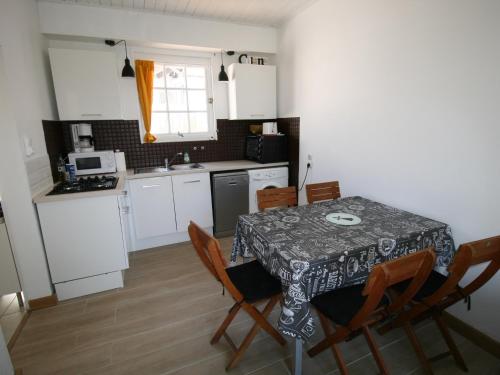 une cuisine avec une table et des chaises et une cuisine avec des armoires blanches dans l'établissement À 100m de la plage, maison idéale avec terrasse et équipements complets - FR-1-22-321, à La Tranche-sur-Mer