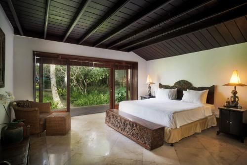 a bedroom with a large bed and a large window at Villa Puri Tupai in Ubud