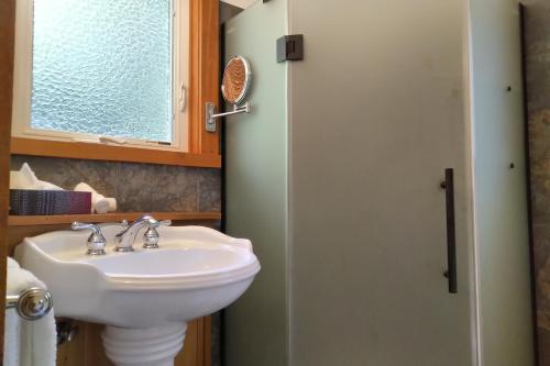 La salle de bains est pourvue d'un lavabo blanc et d'une fenêtre. dans l'établissement Moon Dance Cabin, à Madeira Park