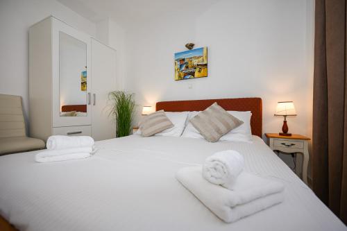 a bedroom with a white bed with towels on it at Beach House Poseydon in Mlini