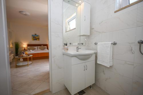 a white bathroom with a sink and a mirror at Beach House Poseydon in Mlini