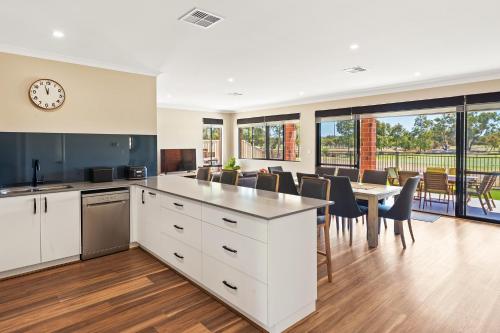 an open kitchen and dining room with a clock on the wall at The Links - fairway views, walk to town, air-con in Dunsborough