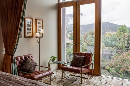 a bedroom with a bed and two chairs and a large window at Islington Hotel in Hobart