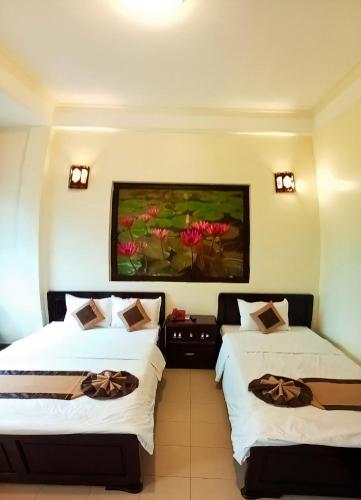 two beds in a room with a painting on the wall at Tran Ly Hotel in Hue