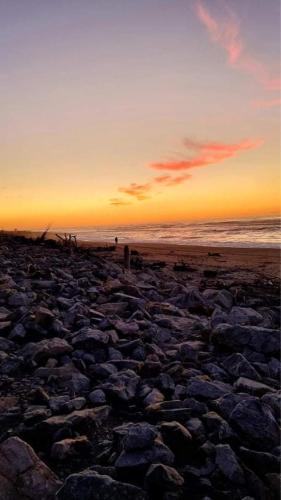 a sunset on a beach with rocks and the ocean at Hokitika - Blue Spur Bed and Breakfast in Hokitika