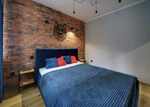 ein Schlafzimmer mit einem blauen Bett und einer Ziegelwand in der Unterkunft Apartament Sun & Ski - Loft in Podgórzyn