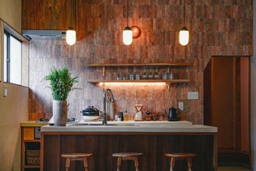 a kitchen with a counter with stools and a sink at Kominkayado LOOF Sakanoie in Fuefuki