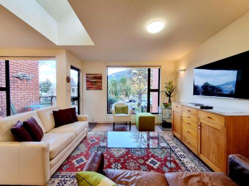 a living room with a couch and a flat screen tv at St James Apartments in Queenstown