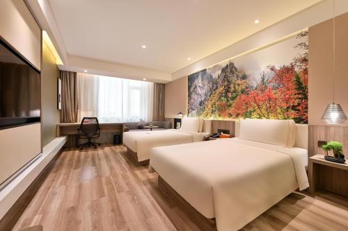 a hotel room with two beds and a painting at Atour Hotel Dalian Zhuanghe in Zhuanghe