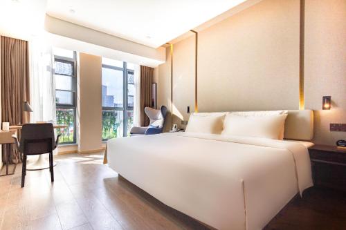 a bedroom with a large white bed and a desk at Atour Hotel Nanchang Red Valley Beach Causeway Bay in Nanchang