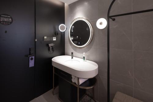 La salle de bains est pourvue d'un lavabo blanc et d'un miroir. dans l'établissement Atour Light Hotel Nanjing Agricultural University, à Nankin