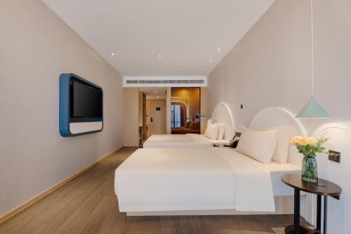 a bedroom with two beds and a tv on a wall at Atour Hotel Nanning Wuxiang Headquarter Base in Nanning