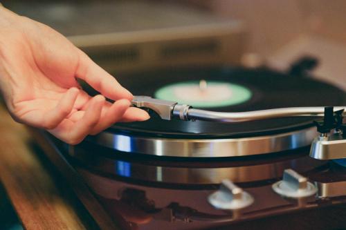 a person holding a knife over a vinyl record at Kominkayado LOOF Sakanoie in Fuefuki