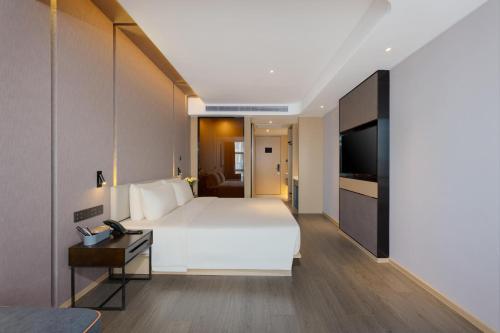 een slaapkamer met een bed, een bureau en een televisie bij Atour Hotel Nanning Wuxiang Headquarter Base in Nanning