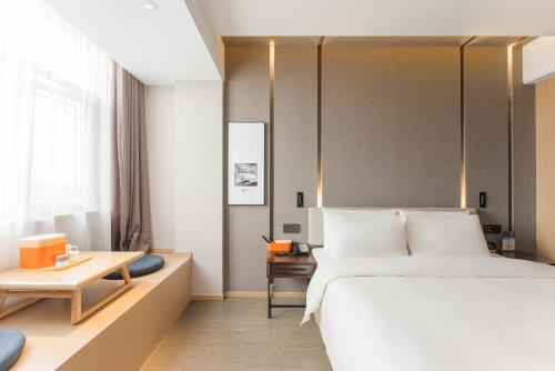a bedroom with a large bed and a table at Atour Hotel Tongxiang Wuzhen in Tongxiang
