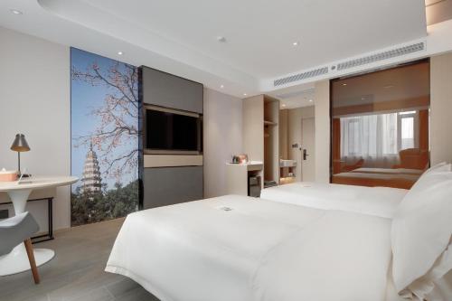 a bedroom with a large white bed and a large window at Atour Hotel Jinan High-Speed East Railway Station in Jinan