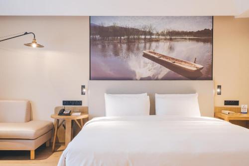 a bedroom with a bed and a picture of a boat on the wall at Atour Hotel Canal Hangzhou in Hangzhou