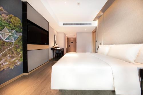 a bedroom with a large white bed and a flat screen tv at Atour Hotel Guiyang Guanshan Lake City Government in Guiyang