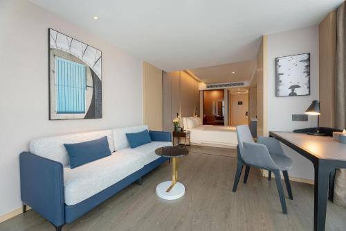a living room with a blue couch and a bedroom at Atour Hotel Nanning Wuxiang Headquarter Base in Nanning