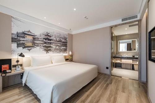 a bedroom with a white bed and a painting on the wall at Atour Hotel Zhenjiang Xijindu Jinshan Temple in Zhenjiang