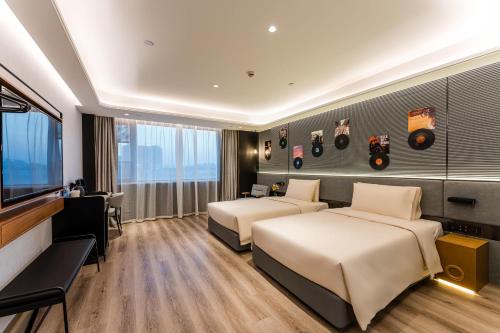 a hotel room with two beds and a desk at Atour X Hotel Renmin Bridge South Metro Panmen Scenic Area Suzhou in Suzhou
