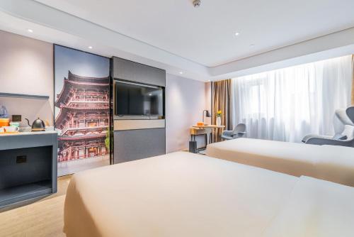 a hotel room with two beds and a flat screen tv at Atour Hotel Xian Hujia Temple in Xi'an