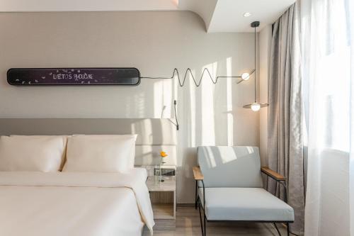 a bedroom with a white bed and a chair at Atour X Hotel Renmin Bridge South Metro Panmen Scenic Area Suzhou in Suzhou