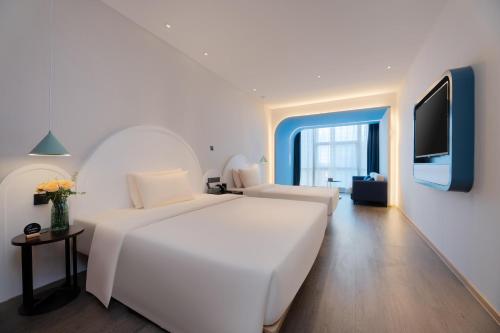 a white bedroom with a large white bed and a tv at Atour Hotel Nanning Wuxiang Headquarter Base in Nanning