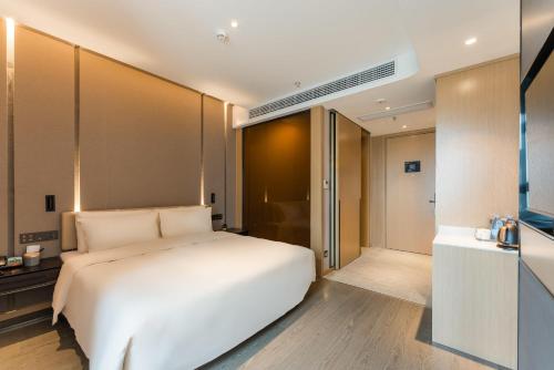 a bedroom with a white bed and a bathroom at Atour Hotel Nanchang Red Valley Beach Qiushui Plaza in Nanchang
