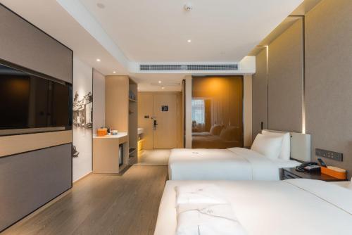 a hotel room with two beds and a flat screen tv at Atour Hotel Tongxiang Wuzhen in Tongxiang