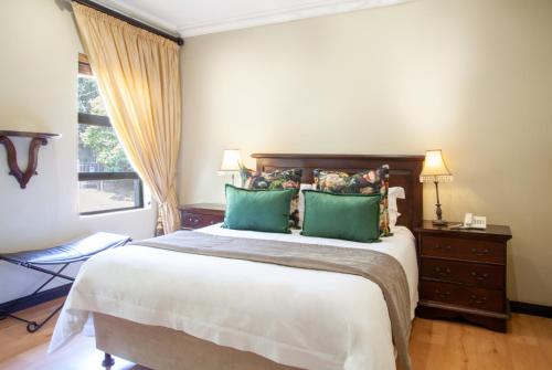 a bedroom with a large bed with green pillows at InnJoy Boutique Hotel in Centurion