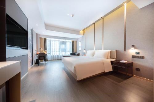 a bedroom with a large white bed and a desk at Atour Hotel Guiyang Guanshan Lake City Government in Guiyang