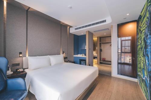 a bedroom with a large white bed and a blue chair at Atour Hotel Ningbo Jishi Harbor Outlets in Ningbo