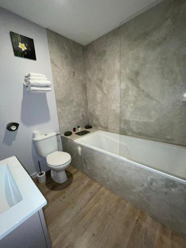 a bathroom with a tub and a toilet and a sink at Logis Hôtel du Large in Plougonvelin