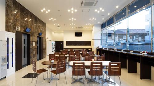 Toyoko Inn Chiba Makuhari في شيبا: مطعم بطاولات وكراسي وبار