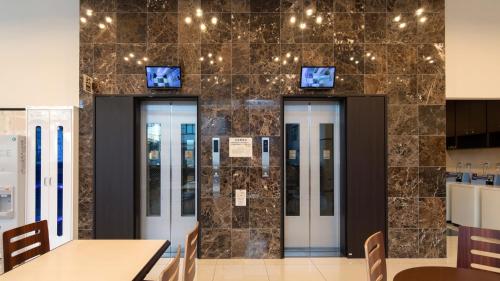 a lobby with four elevators and a wall of tiles at Toyoko Inn Chiba Makuhari in Chiba