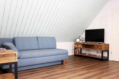 a living room with a blue couch and a tv at Lieblingshaus Fiete in Prerow