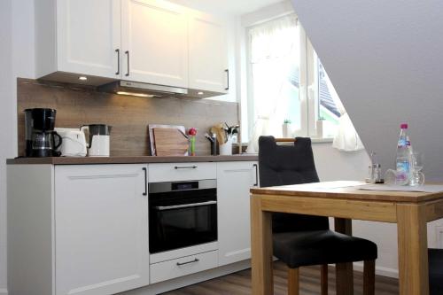 a kitchen with white cabinets and a wooden table at Lieblingshaus Fiete in Prerow