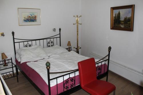 a bedroom with a bed and a red chair at Appartement Eveline in Velden am Wörthersee