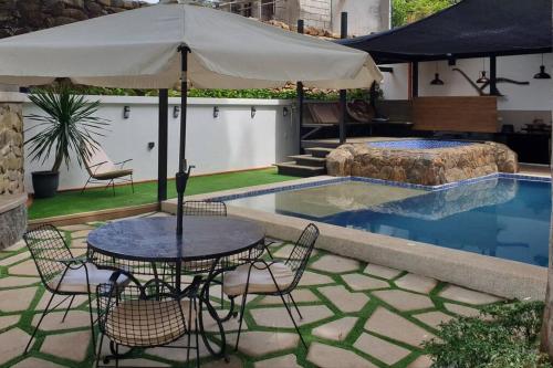 a table with an umbrella next to a swimming pool at CAMP TREEHOUSE • COTTAGE • POOL • JACUZZI in Antipolo
