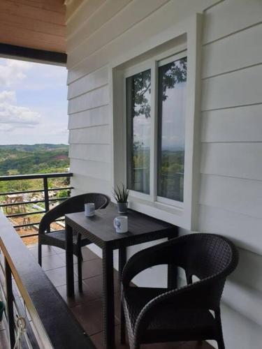 a porch with two chairs and a table on a balcony at CAMP TREEHOUSE • COTTAGE • POOL • JACUZZI in Antipolo