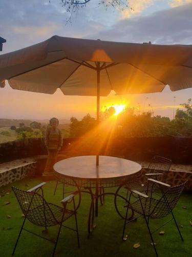 a table and chairs under an umbrella with the sunset at CAMP TREEHOUSE • COTTAGE • POOL • JACUZZI in Antipolo