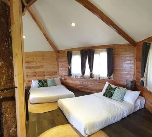 two beds in a room with wooden walls and windows at CAMP TREEHOUSE • COTTAGE • POOL • JACUZZI in Antipolo