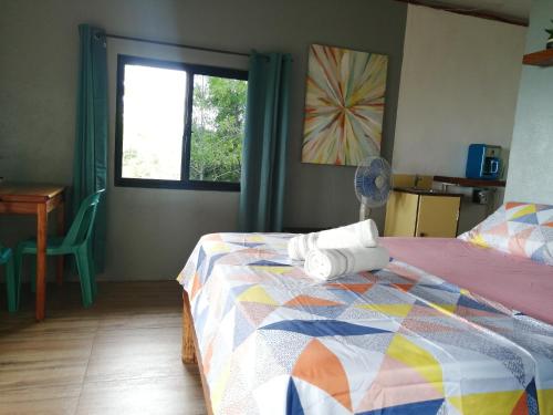 Un dormitorio con una cama con un edredón colorido y una ventana en Shambala Paradise, en Siquijor
