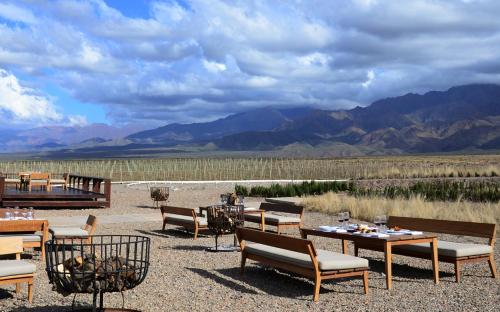 a restaurant with tables and chairs with mountains in the background at Casa de Uco Vineyards and Wine Resort in Los Árboles