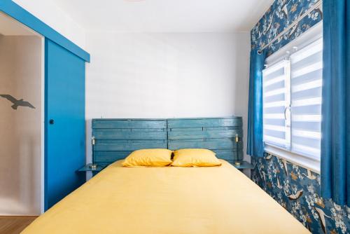 a bed with yellow pillows in a blue bedroom at Cajem in Étretat
