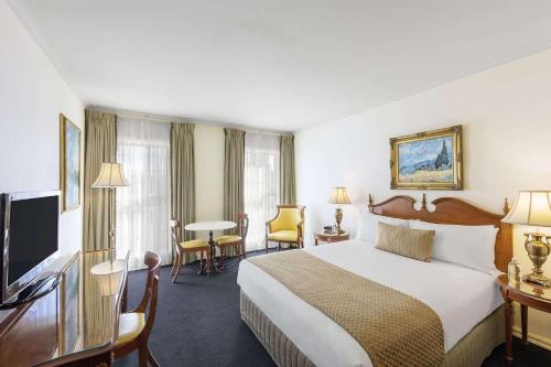 a hotel room with a bed and a flat screen tv at Canterbury International Hotel in Forest Hill