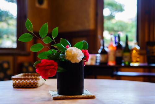 a black vase with red and white flowers on a table at Yamada Bessou in Beppu