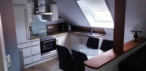 een keuken met een tafel, een wastafel en een raam bij Ferienwohnung Anna in Marienhafe